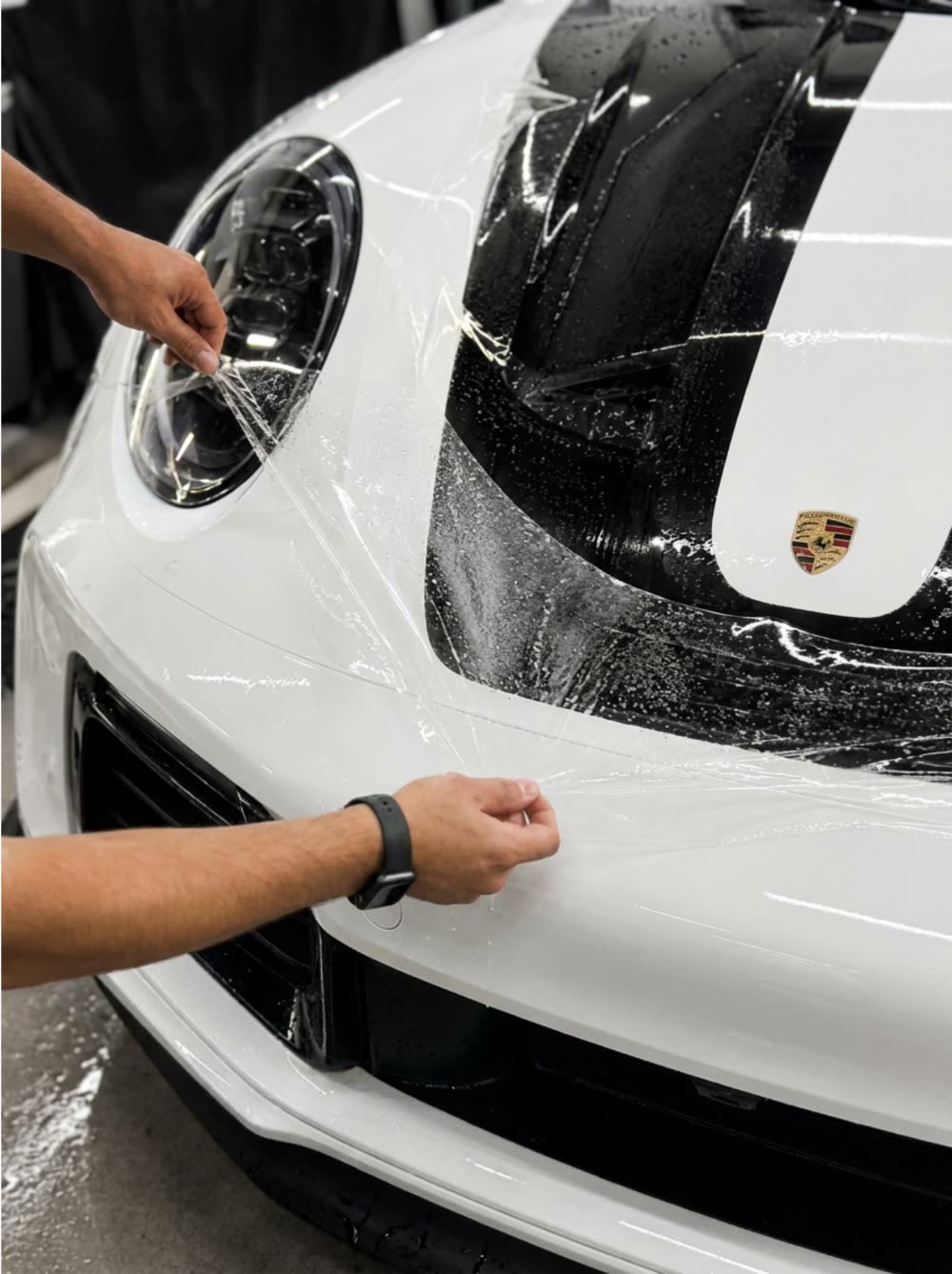 Paint protection film being smoothed onto a Porsche bumper